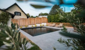 Piscine carrée chez un particulier avec aménagement extérieur.